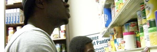 Individuals looking at canned goods on shelves in the Jamil Niner Student Pantry.