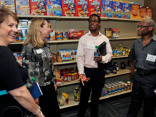 Group of individuals standing in front of shelves of pantry items.