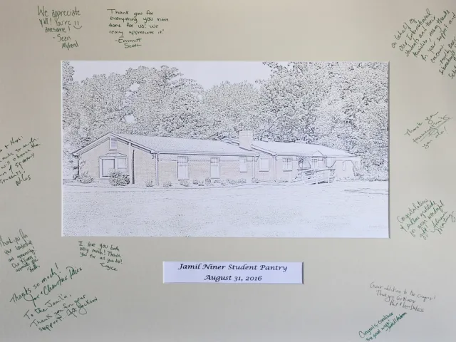 Framed picture of the pantry building with handwritten notes from students on frame. Text at bottom reads Jamil Niner Student Pantry August 31, 2016.